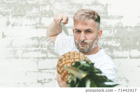 Stylish caucasian attractive chef with pineapple on a brick wall background. 71442917