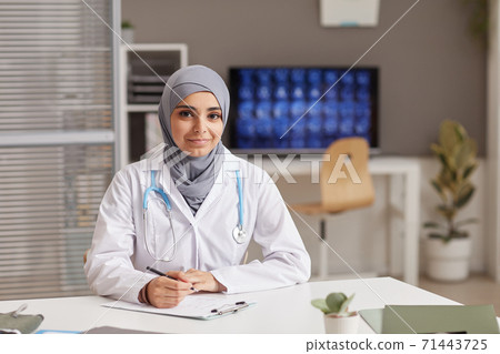 Female doctor sitting at office Female doctor sitting at office 71443725