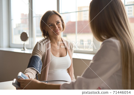 Doctor measuring blood pressure of her pregnant patient Doctor measuring blood pressure of her pregnant patient 71446054