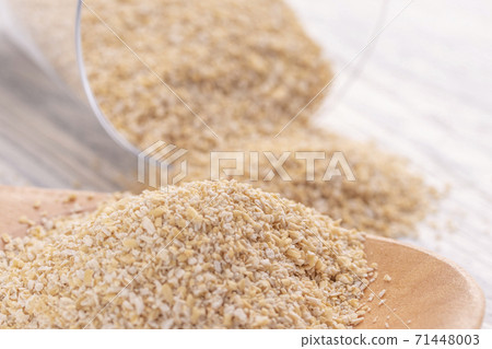 Oat bran in a wooden spoon and in a glass transparent glass on a white wooden table. The concept of good nutrition for weight loss and health 71448003