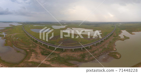 Aerial view of Thai local train on railway bridge at Pa Sak Jolasid Dam, the biggest reservoir in central Thailand, in Lopburi province with cloudy sky in transportation and travel concept. 71448228