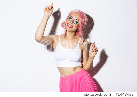 Image of attractive party girl with pink wig and bright makeup, having fun and celebrating holiday, dancing happy over white background Image of attractive party girl with pink wig and bright makeup, having fun and celebrating holiday, dancing happy over white background 71448452
