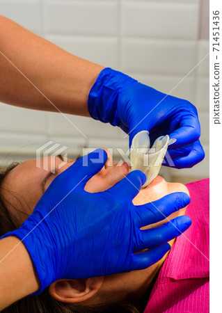 A young female dentist pulls a mouth extender at a dental clinic. Mouth dilator and retractor. 71451436
