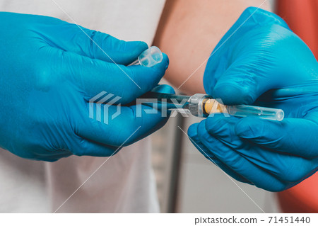 The dentist holds a carpule syringe, injects for injection into the oral cavity, local anesthesia. The dentist holds a carpule syringe, injects for injection into the oral cavity, local anesthesia. 71451440