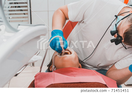 The dentist uses a scaler to remove tartar, oral hygiene. 71451451