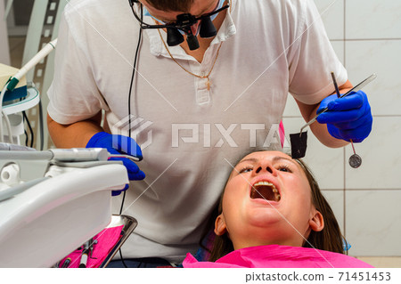 After filling, the dentist removes the excess material from the tooth with a copying tracing paper. 71451453