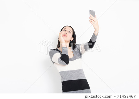 A woman taking self in herself with a smartphone A woman taking self in herself with a smartphone 71452467