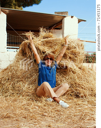 Young woman sitting near haystack Young woman sitting near haystack 71453175