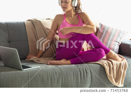 Beautiful young woman working out indoors, doing yoga exercise on gray mat at home 71453768