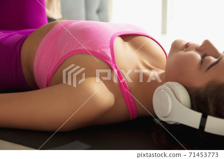 Beautiful young woman working out indoors, doing yoga exercise on gray mat at home Beautiful young woman working out indoors, doing yoga exercise on gray mat at home 71453773