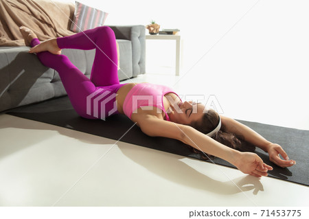 Beautiful young woman working out indoors, doing yoga exercise on gray mat at home 71453775