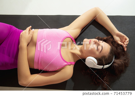 Beautiful young woman working out indoors, doing yoga exercise on gray mat at home Beautiful young woman working out indoors, doing yoga exercise on gray mat at home 71453779