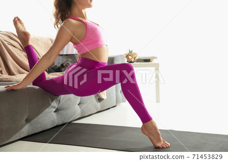 Close up young woman working out indoors, doing yoga exercise on gray mat at home 71453829
