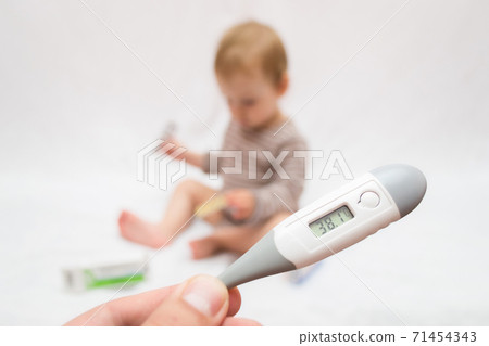hand holds a thermometer with a high temperature on a white isolated background child with pills hand holds a thermometer with a high temperature on a white isolated background child with pills 71454343