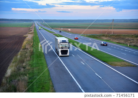 Truck with semi-trailer driving along highway on the sunset background. Truck with semi-trailer driving along highway on the sunset background. 71456171