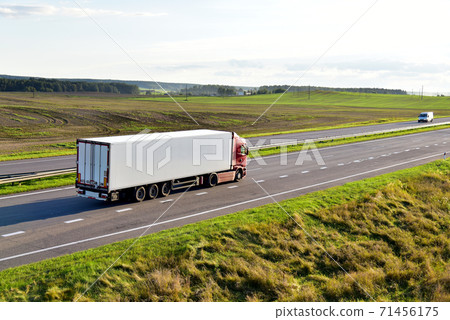 White truck with semi-trailer driving along highway on the sunset background.  71456175