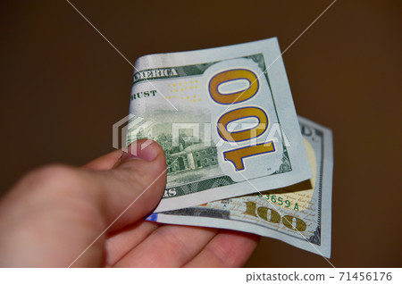 US one hundred dollar bills in mans hand.  71456176