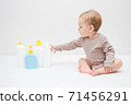 beautiful baby holding a bottle in the hand with shower gel, beside lies Baby cosmetic tubes on white isolated background 71456291