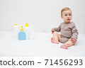 beautiful baby holding a bottle in the hand with shower gel, beside lies Baby cosmetic tubes on white isolated background 71456293
