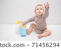 beautiful baby holding a bottle in the hand with shower gel, beside lies Baby cosmetic tubes on white isolated background 71456294