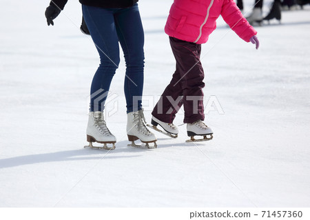 child and adult skates at the ice rink. child and adult skates at the ice rink. 71457360
