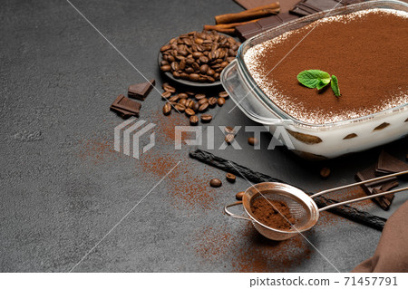 Traditional Italian Tiramisu dessert in glass baking dish and pieces of chocolate bar on concrete background Traditional Italian Tiramisu dessert in glass baking dish and pieces of chocolate bar on concrete background 71457791