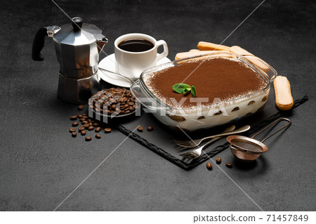 Traditional Italian Tiramisu dessert in glass baking dish, coffee maker, savoiardi cookies and cup of fresh hot espresso coffee on concrete background Traditional Italian Tiramisu dessert in glass baking dish, coffee maker, savoiardi cookies and cup of fresh hot espresso coffee on concrete background 71457849