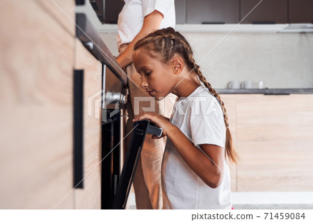 Girl looking cookies from oven 71459084