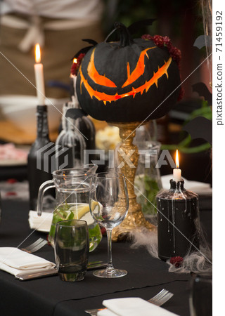 Table set for Halloween dinner. Served holiday table with candles and pumpkin Table set for Halloween dinner. Served holiday table with candles and pumpkin 71459192