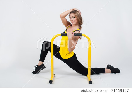 Woman doing exercises with high yellow floor bars on a white background Woman doing exercises with high yellow floor bars on a white background 71459307