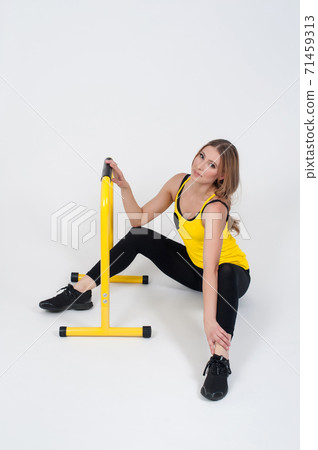 Woman doing exercises with high yellow floor bars on a white background 71459313