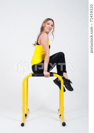 Woman doing exercises with high yellow floor bars on a white background 71459320