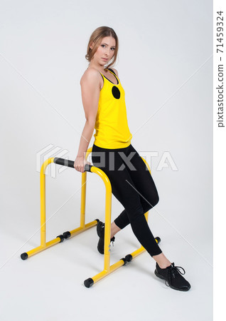 Woman doing exercises with high yellow floor bars on a white background Woman doing exercises with high yellow floor bars on a white background 71459324