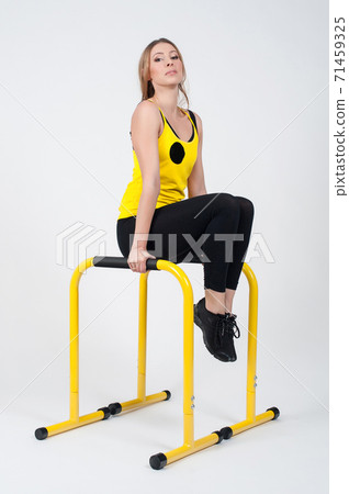 Woman doing exercises with high yellow floor bars on a white background Woman doing exercises with high yellow floor bars on a white background 71459325