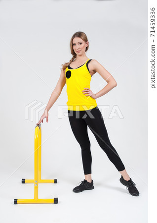 Woman doing exercises with high yellow floor bars on a white background 71459336