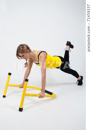 Woman doing exercises with high yellow floor bars on a white background Woman doing exercises with high yellow floor bars on a white background 71459337