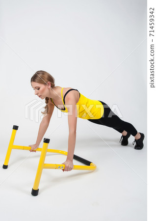 Woman doing exercises with high yellow floor bars on a white background Woman doing exercises with high yellow floor bars on a white background 71459342