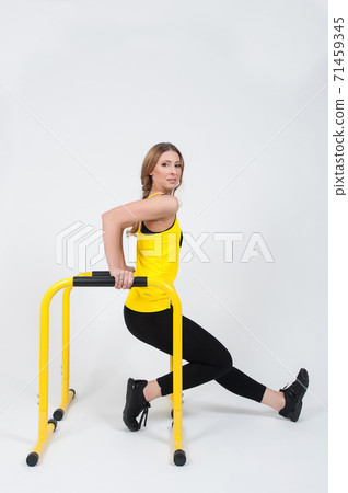 Woman doing exercises with high yellow floor bars on a white background Woman doing exercises with high yellow floor bars on a white background 71459345