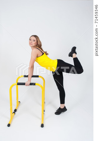 Woman doing exercises with high yellow floor bars on a white background Woman doing exercises with high yellow floor bars on a white background 71459346