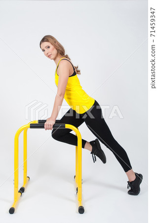 Woman doing exercises with high yellow floor bars on a white background Woman doing exercises with high yellow floor bars on a white background 71459347