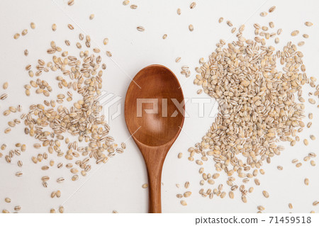 Wood spoon with unhulled barley on white background 71459518