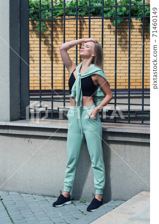 Stylish beautiful young blond woman in a light green tracksuit posing on the street. Attractive girl model posing outdoors Stylish beautiful young blond woman in a light green tracksuit posing on the street. Attractive girl model posing outdoors 71460149
