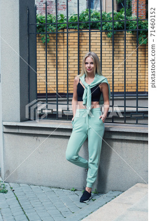 Stylish beautiful young blond woman in a light green tracksuit posing on the street. Attractive girl model posing outdoors Stylish beautiful young blond woman in a light green tracksuit posing on the street. Attractive girl model posing outdoors 71460152