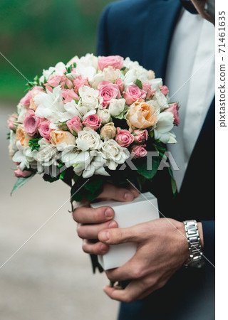 fiance in a dark blue suit holds a wedding bouquet fiance in a dark blue suit holds a wedding bouquet 71461635