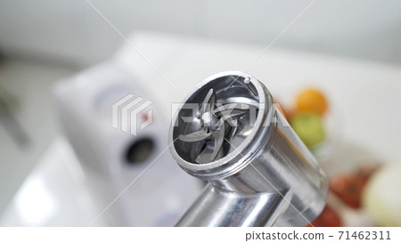 Female hand sets knife in meat grinder for providing high-quality mince from all types of meat. Electric mincer machine for minced meat per minute, make sausages, mashed berries, squeeze juice. 71462311