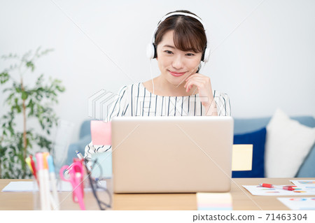 Telework smiling young woman wearing white headphones at home for a web conference 71463304