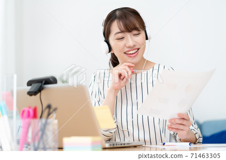 Telework smiling young woman wearing white headphones at home for a web conference 71463305