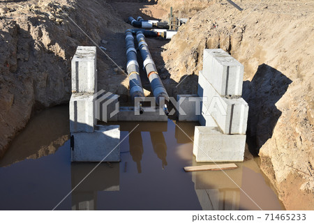 Laying heating pipes in a trench at construction site. Laying heating pipes in a trench at construction site. 71465233