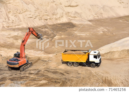 Excavator load the sand to the heavy dump truck in the open-pit. Heavy machinery 71465256