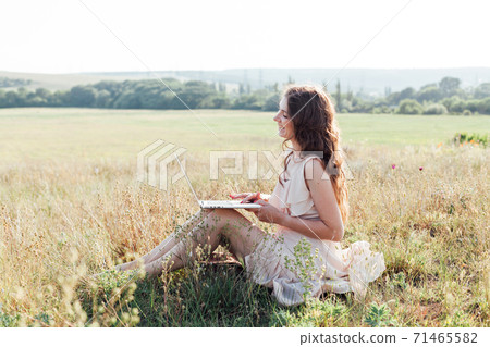 Woman works on laptop on internet remotely outdoors 71465582